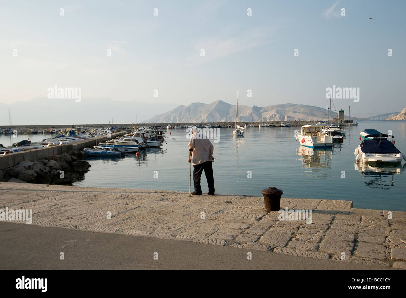 An elderly man walks on the dock of the port Stock Photo