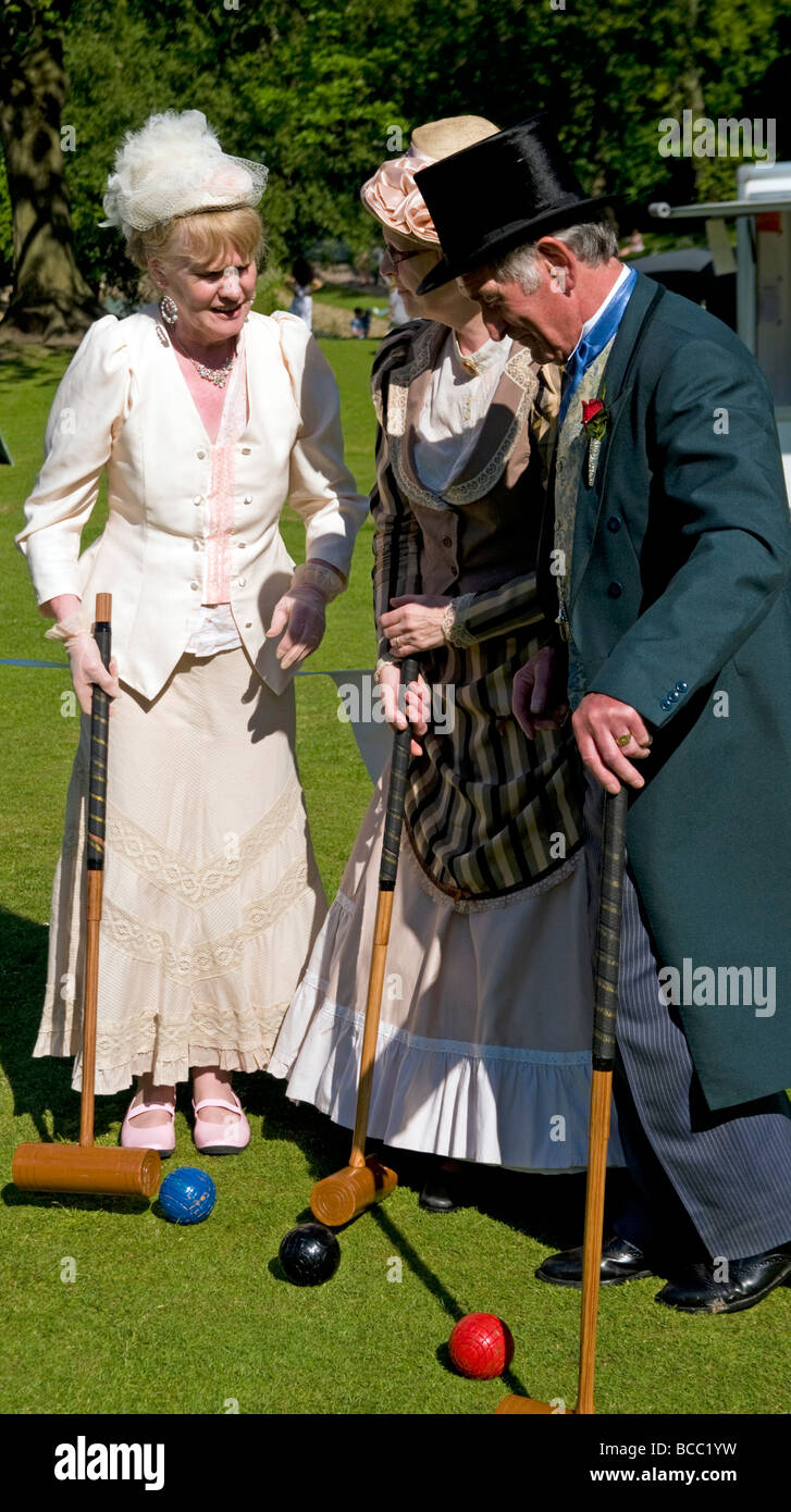 People dressed in Victorian clothes playing the lawn game of croquet in