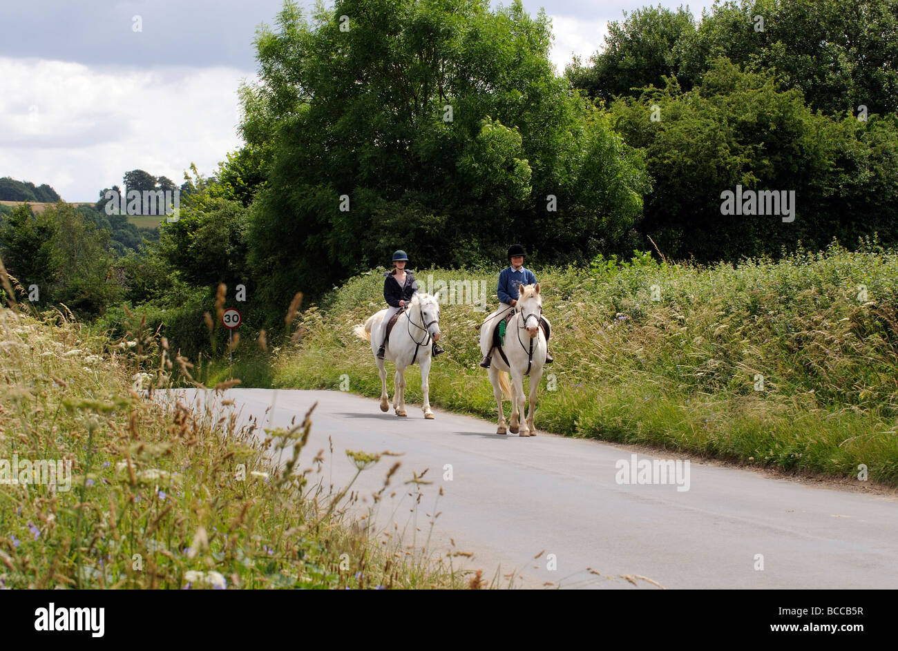 Horse riders on a country road in the Cotswolds Gloucestershire England UK Stock Photo