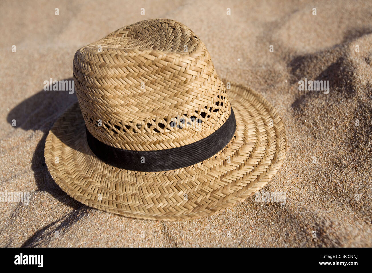 A straw hat with a black ribbon on sand Stock Photo