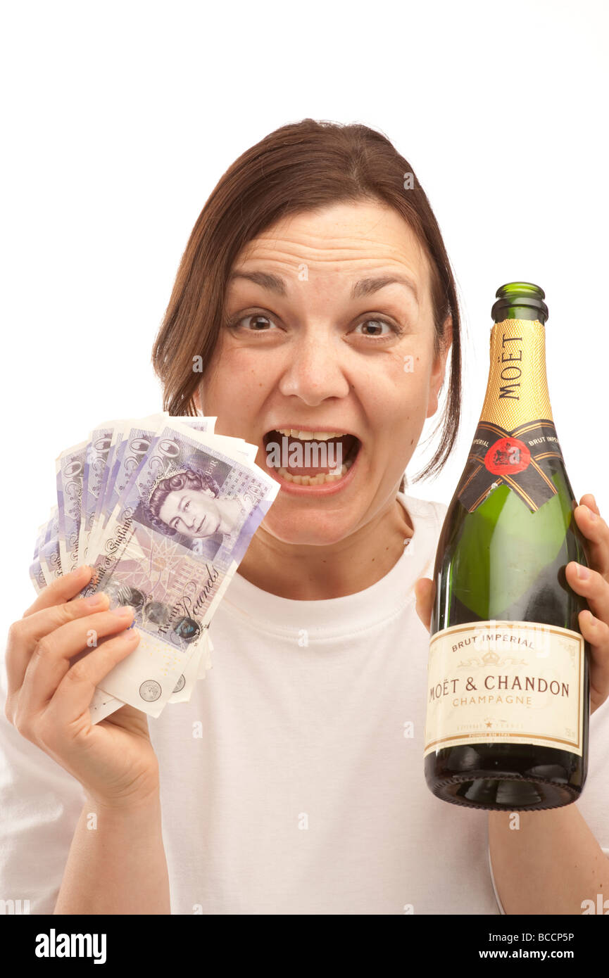 a happy laughing young woman with a hand full of 20 notes cash and a bottle of champagne, UK Stock Photo