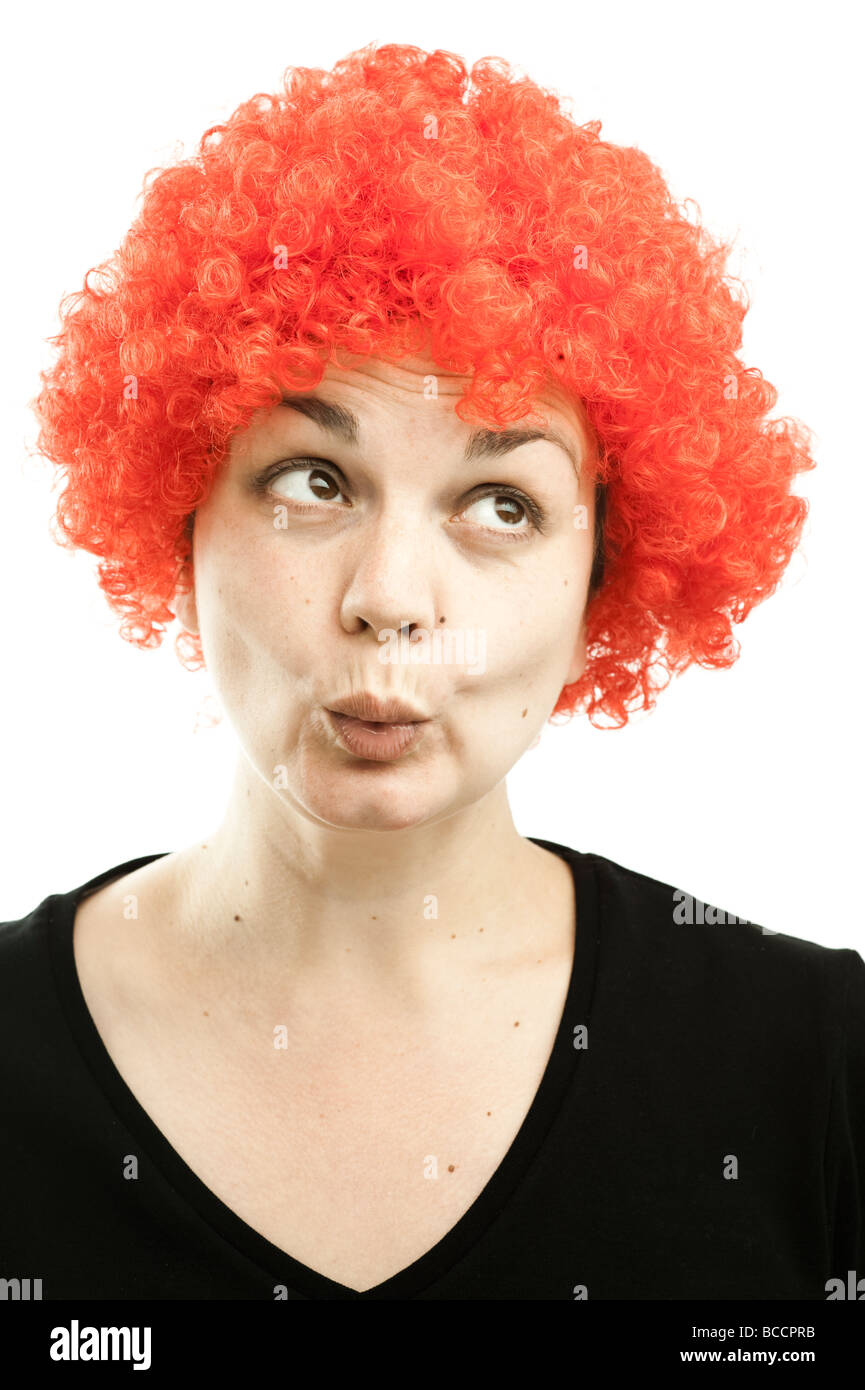 a woman wearing a cheap curly red clown's wig Stock Photo