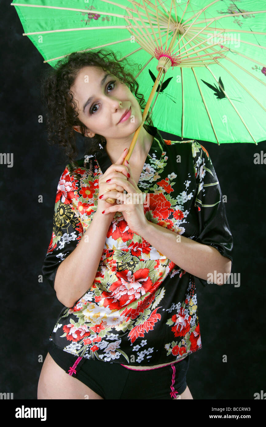 Dark Haired Portuguese Woman Holding a Green Umbrella and Smiling Stock Photo