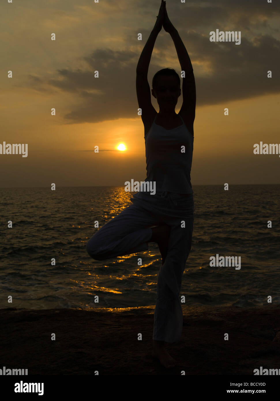 woman doing yoga tree pose by the seaside with sunset sunrise Stock ...