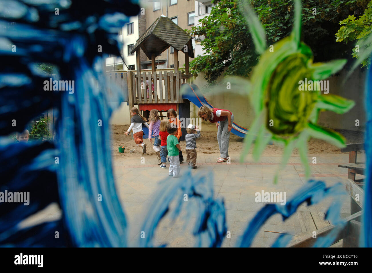 Children and teacher playing on a playground in a kindergarten on a summer day. Stock Photo
