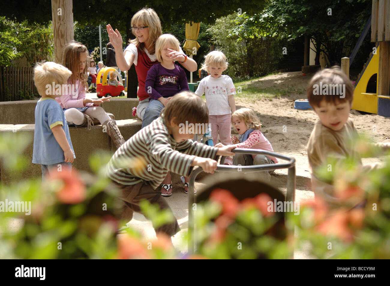 Children and teacher playing on a playground in a kindergarten on a summer day. Stock Photo