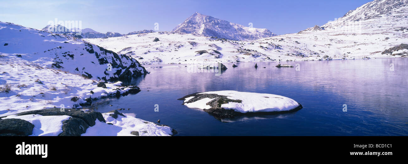 Snowy island in frozen corrie lake. Llyn y cuum ffynnon with Crib Goch. Snowdonia National Park. Wales. Stock Photo