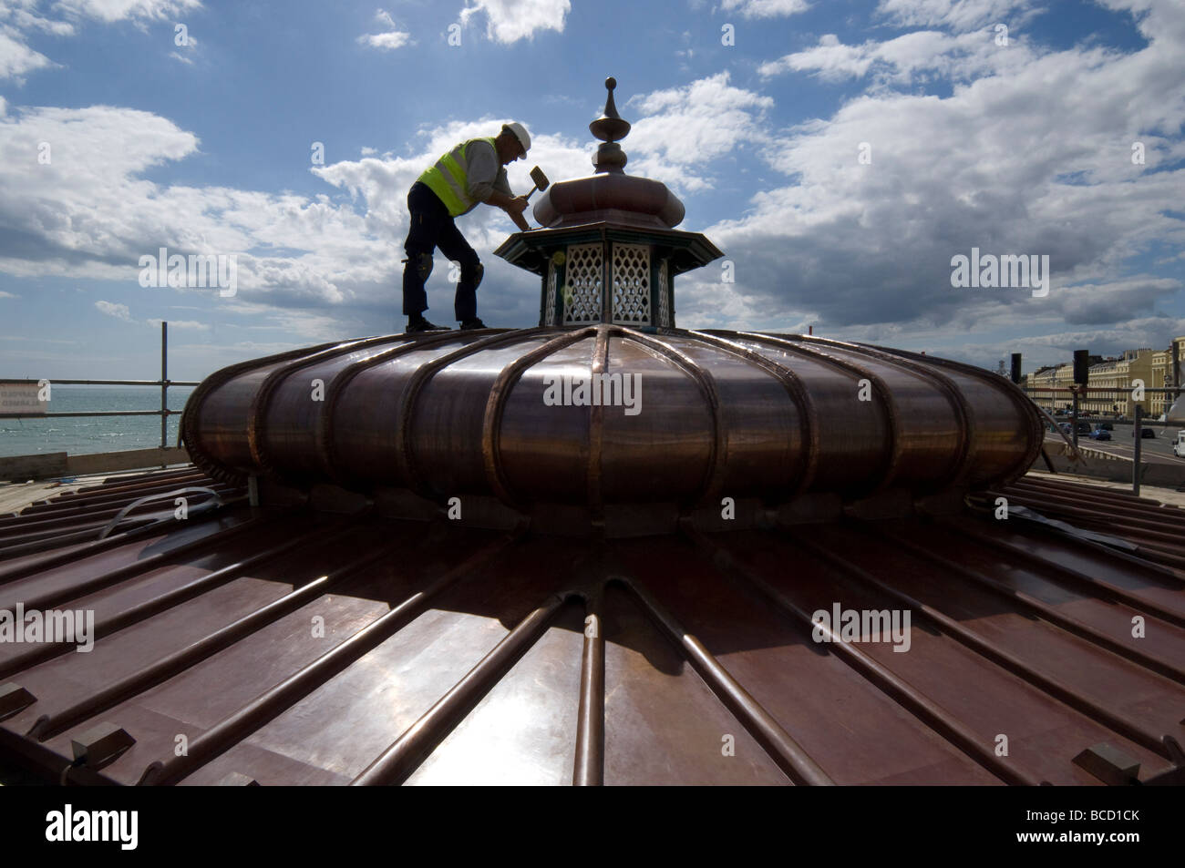 A workman hammering a new copper roof onto a Victorian bandstand on Brighton and Hove seafront Stock Photo
