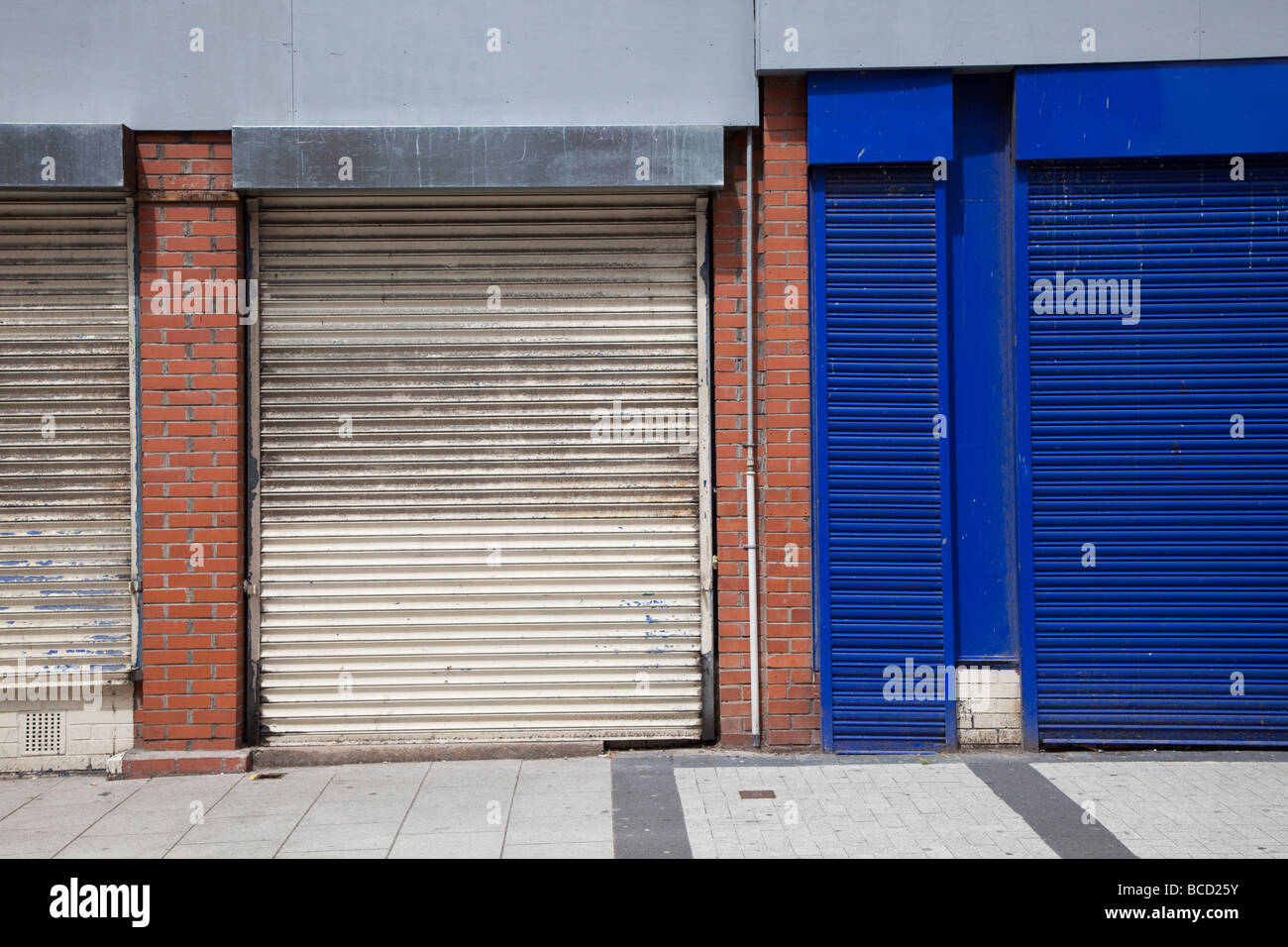 Old white and blue shutters over closed shops in main street Barry Wales UK Stock Photo