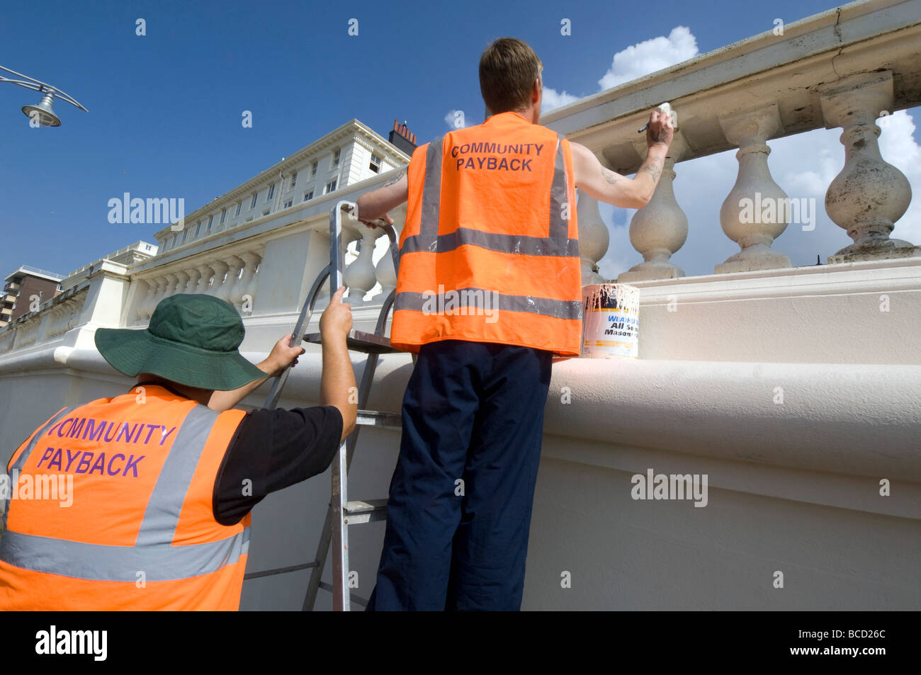 Convicted criminals doing painting and decorating in orange tabards with community payback slogan on the back Stock Photo
