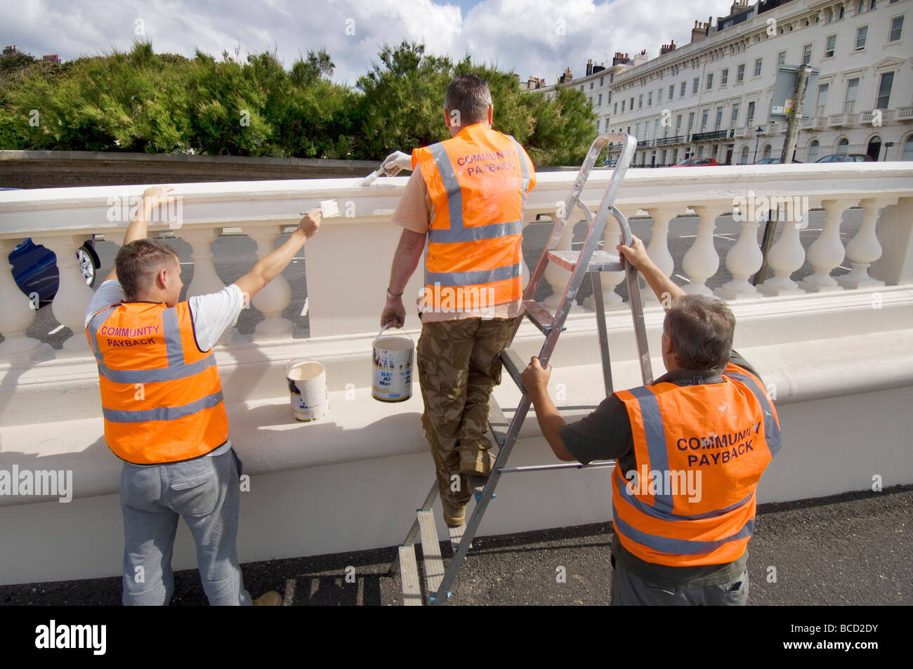 Convicted criminals doing painting and decorating in orange tabards with community payback slogan on the back Stock Photo