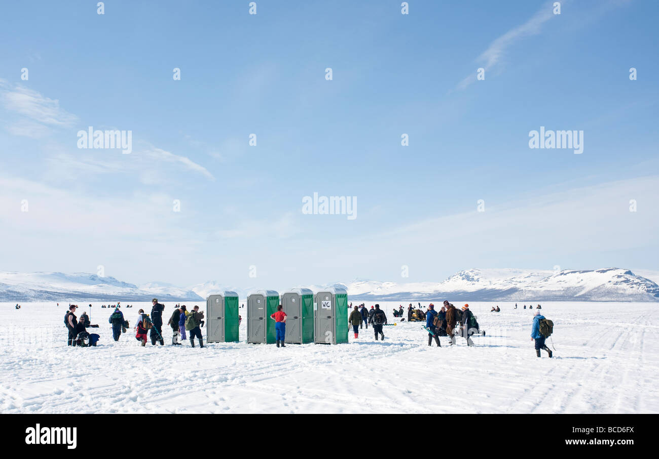 Tourists queuing to outhouses at Lake Kilpisjärvi ice during 'Vain 2 kalaa' ice fishing competition, Lapland , Finland Stock Photo