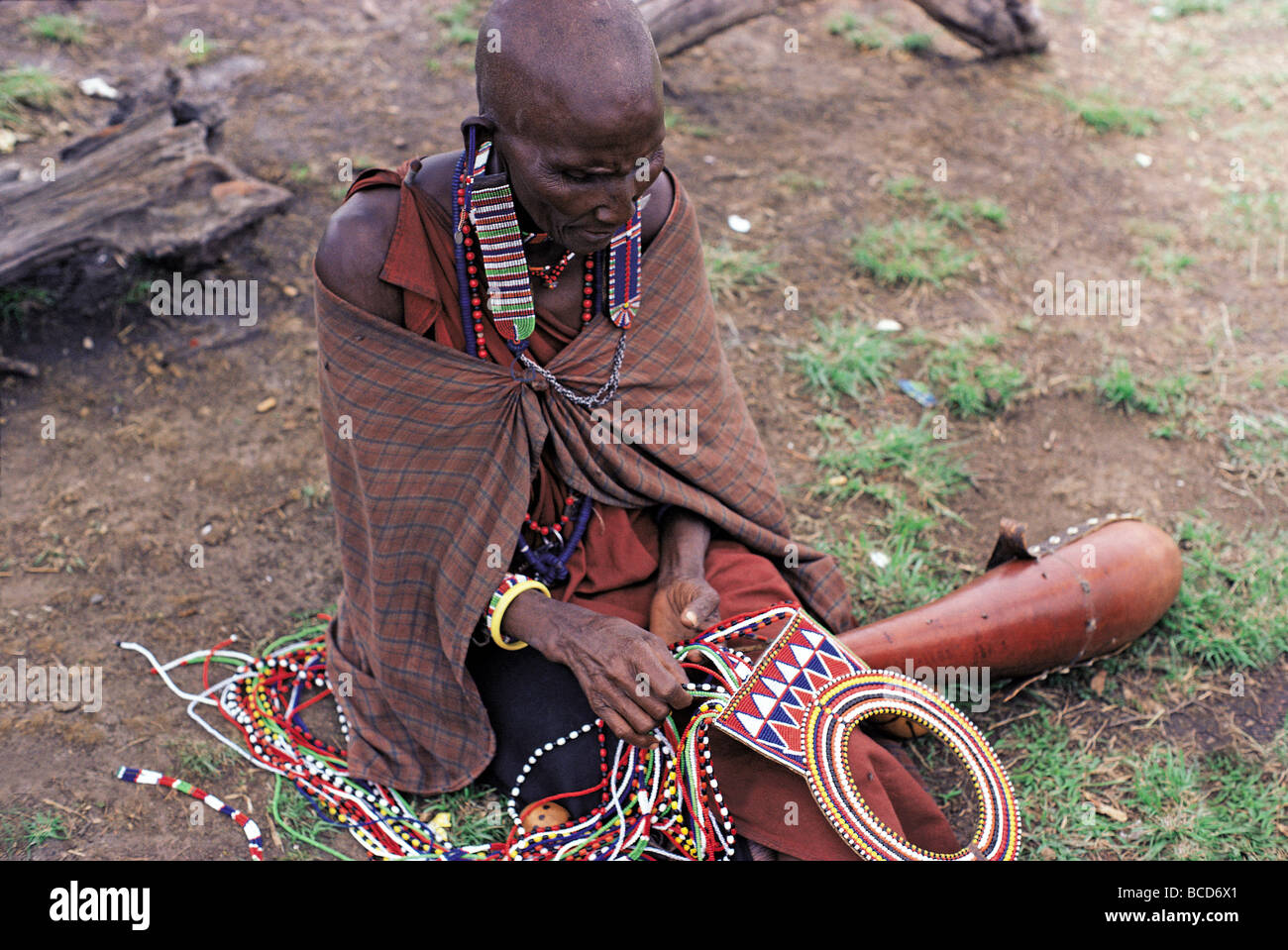 Maasai married woman with shaved head making traditional bead necklace Masai Mara National Reserve Kenya East Africa Stock Photo