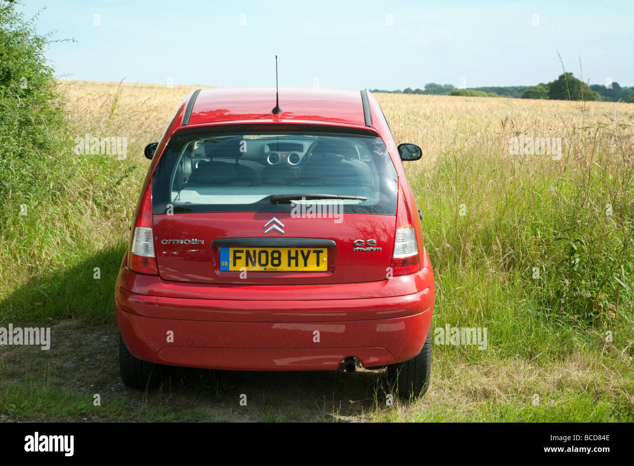 A red car parked on the edge of a cornfield, Essex, England Stock Photo