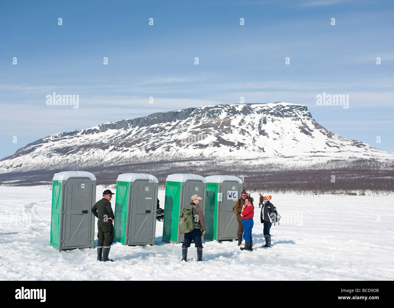 People queuing to mobile outhouses at Lake Kilpisjärvi ice during 'Vain 2 kalaa' ice-fishing competition Saanatunturi Fjell at background , Finland Stock Photo