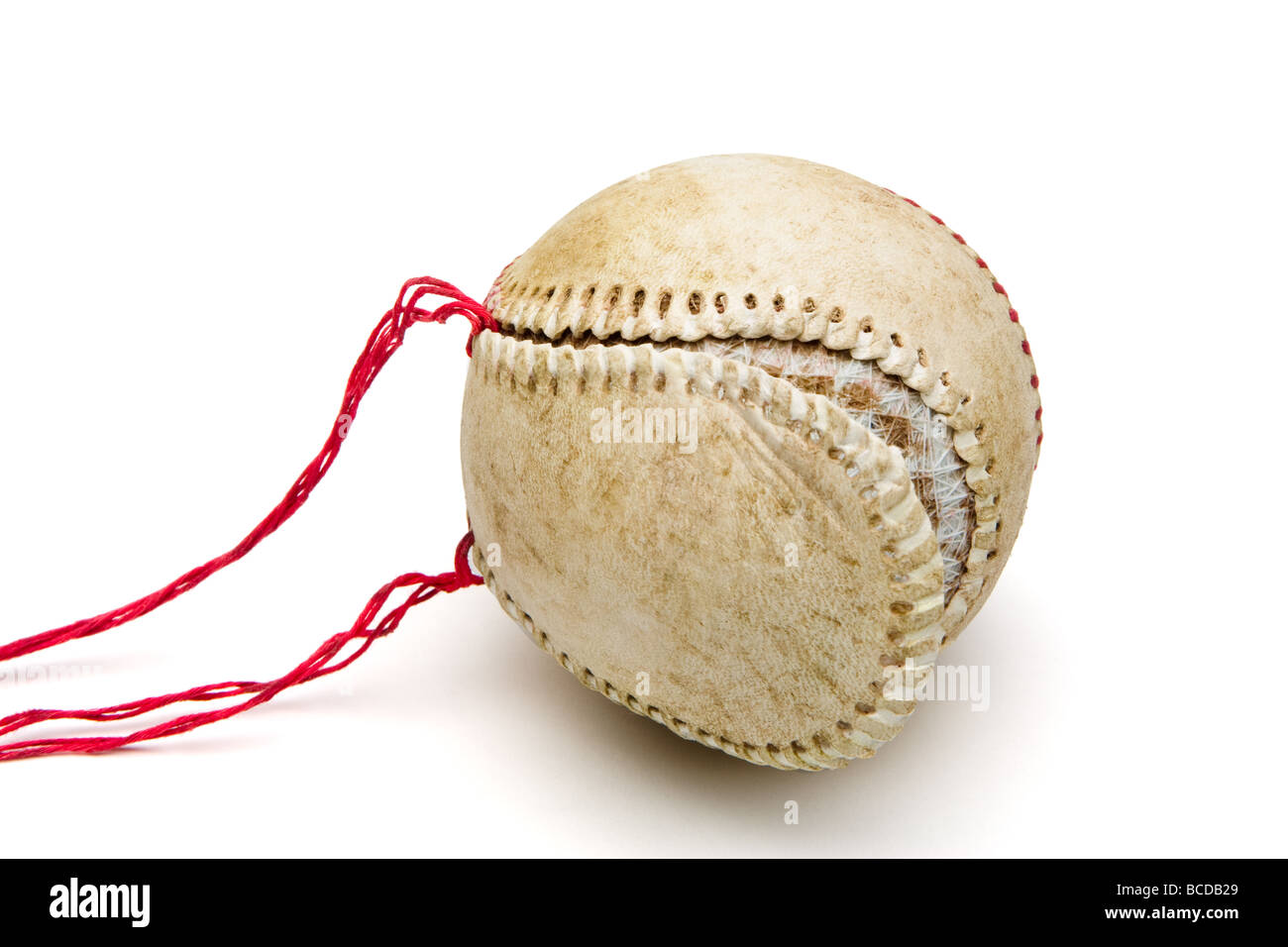 Old worn baseball with red thread seams pulled out and loose leather