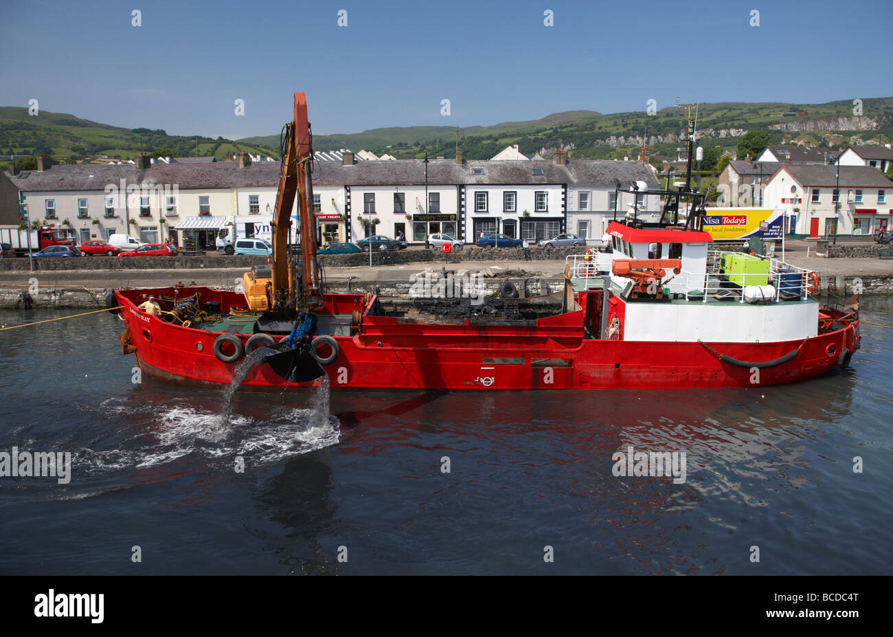 ship containing earth mover dredging carnlough harbour county antrim northern ireland uk Stock Photo