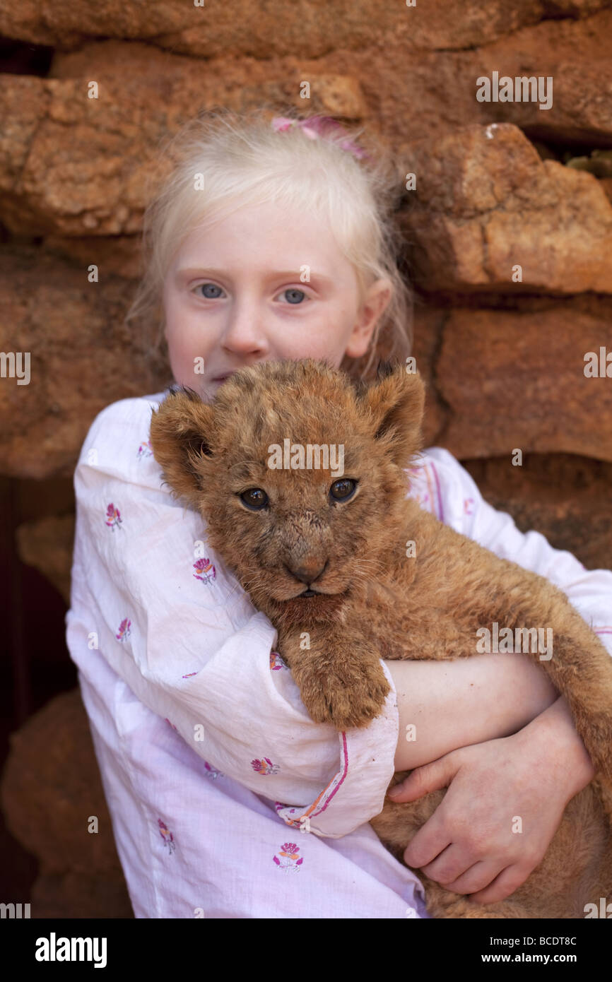 Blonde haired little girl holding lion cub Stock Photo Alamy