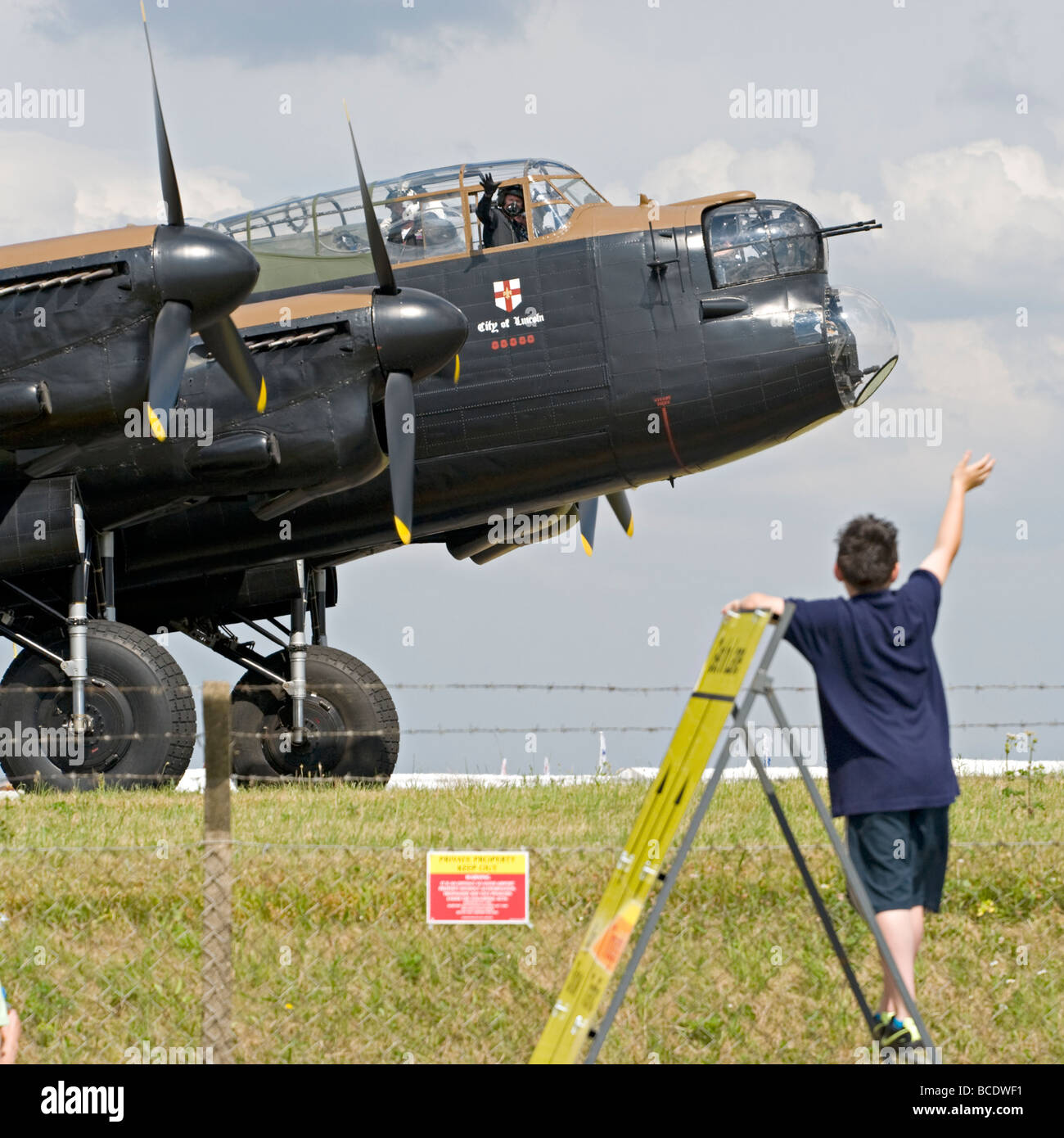 A young boy waves to the crew of the RAF's Lancaster Bomber at Biggin Hill, Kent, England. Stock Photo