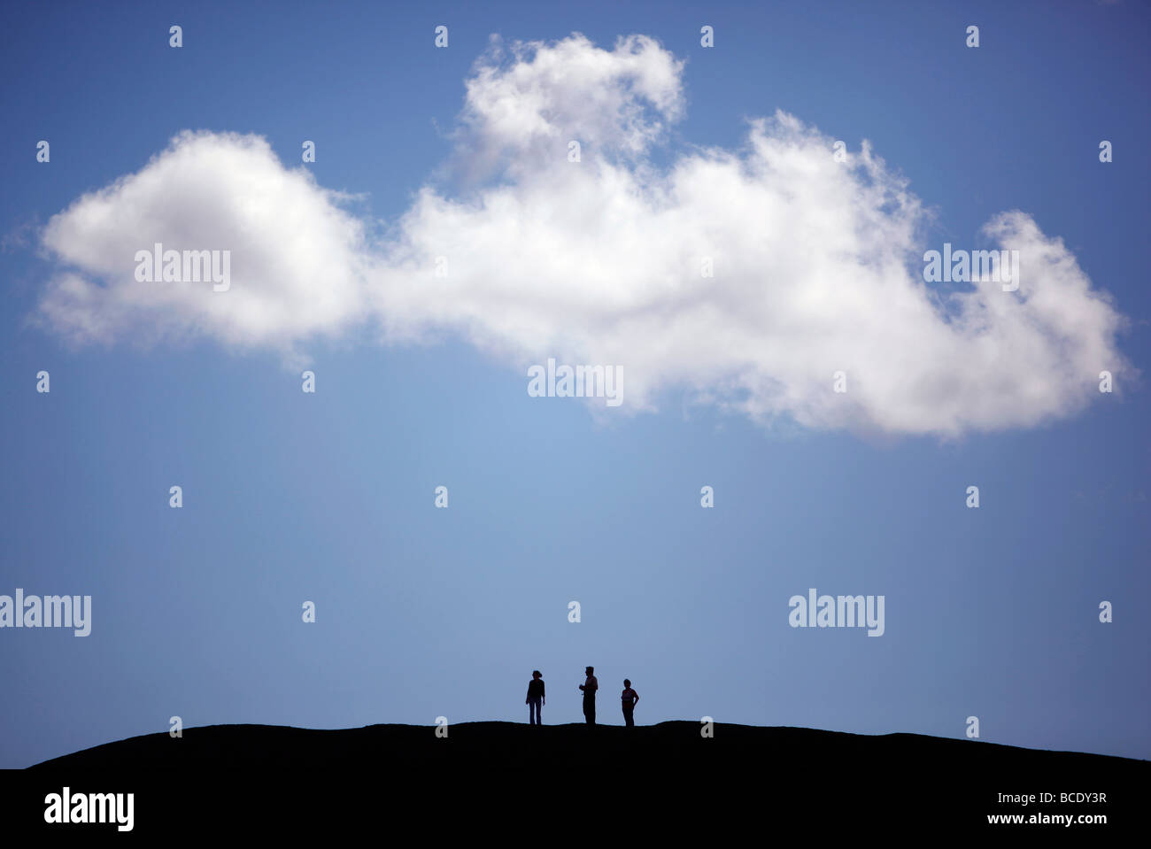 Three people are seen at the edge of Hverfjall, a circular crater in the Mývatn region, Iceland Stock Photo