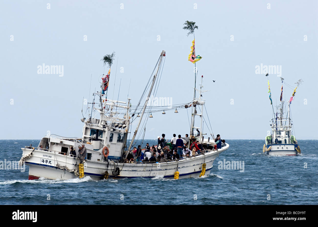 Japanese fishing boats making their way through the choppy Pacific Ocean carrying a crew and some festival goers Stock Photo