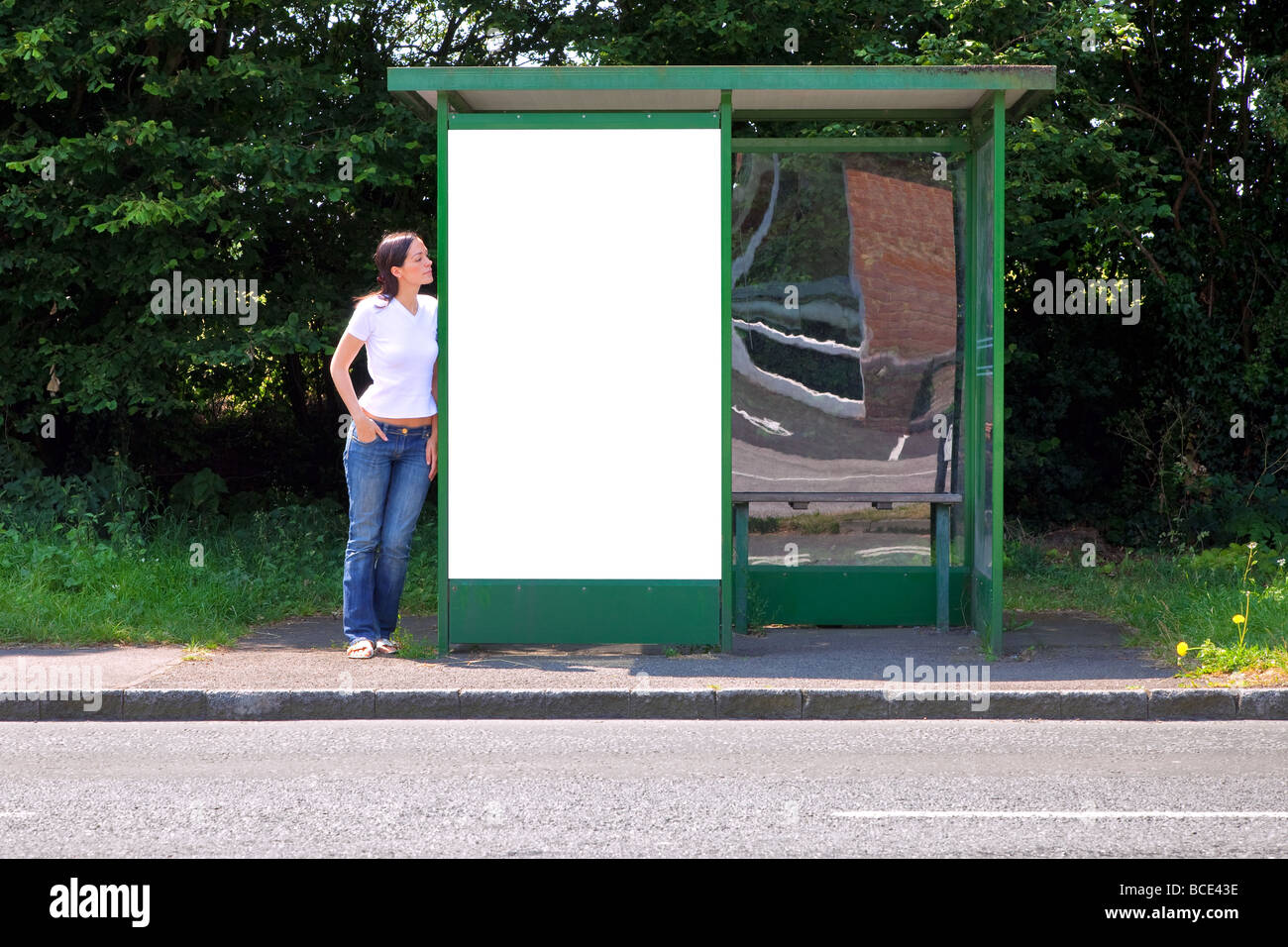 Woman standing at a bus stop with blank billboard for your own message Stock Photo