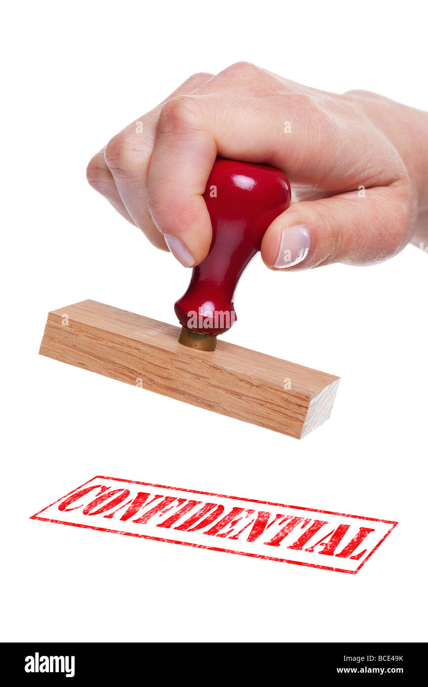 Hand holding a rubber stamp with the word Confidential Stock Photo