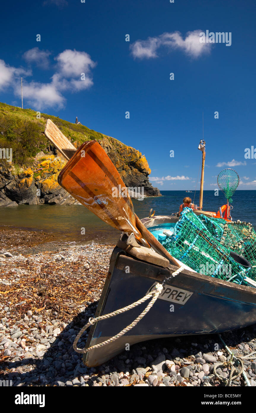 Small fishing boat and oars on the beach at Cadgwith Cove on a bright Summer day on the Cornish coast Cornwall UK Stock Photo