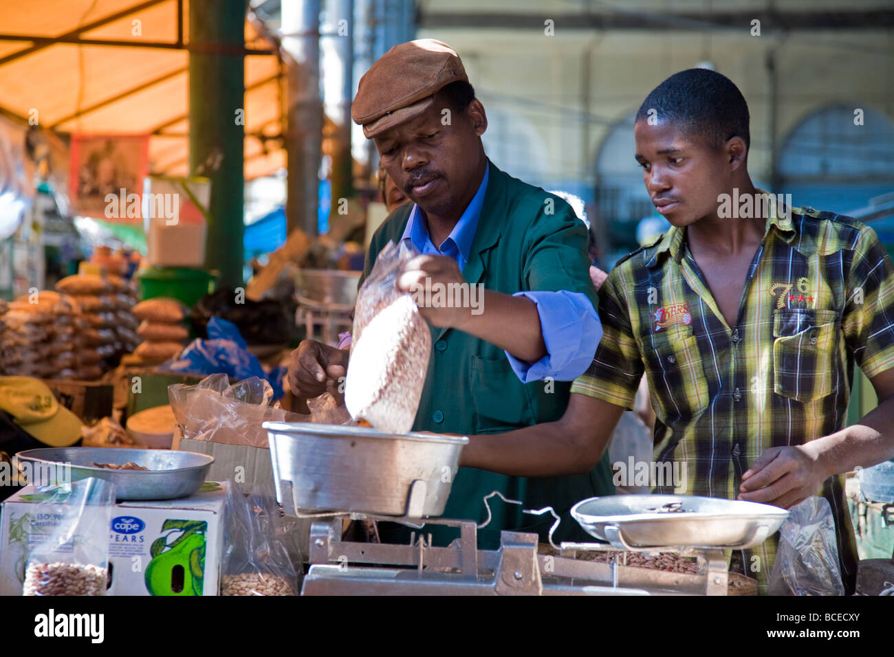 Mozambique, Maputo. A stall holder weighs his produce with the help of his assistant in the Central Market. Stock Photo