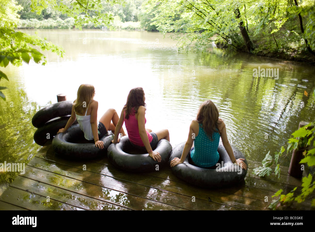 Teenage girls sitting in innertubes on a dock Stock Photo Alamy