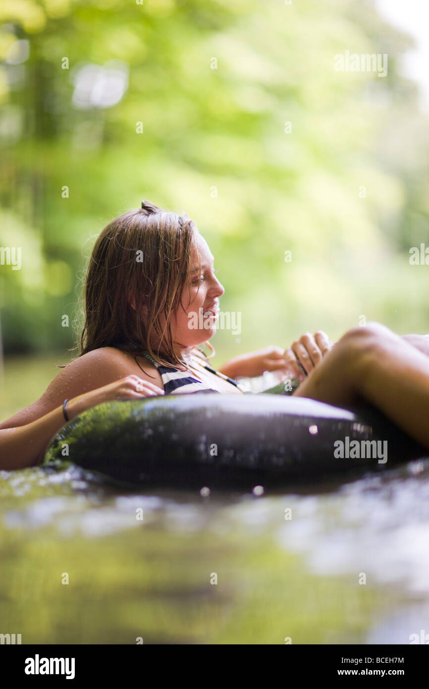 Teenagers sitting in innertubes in the water Stock Photo