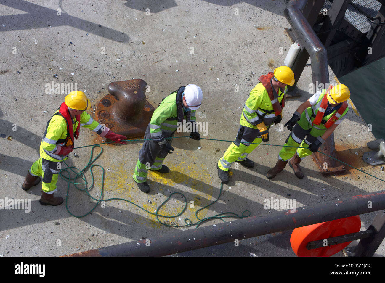 shore crew pull safety line connected to ship rope onto quay while