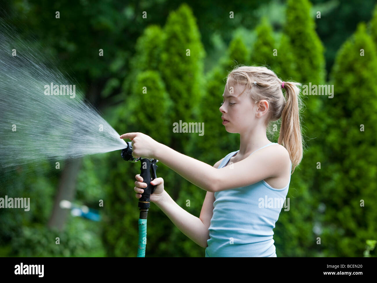 Young girl spraying water with a hose Stock Photo