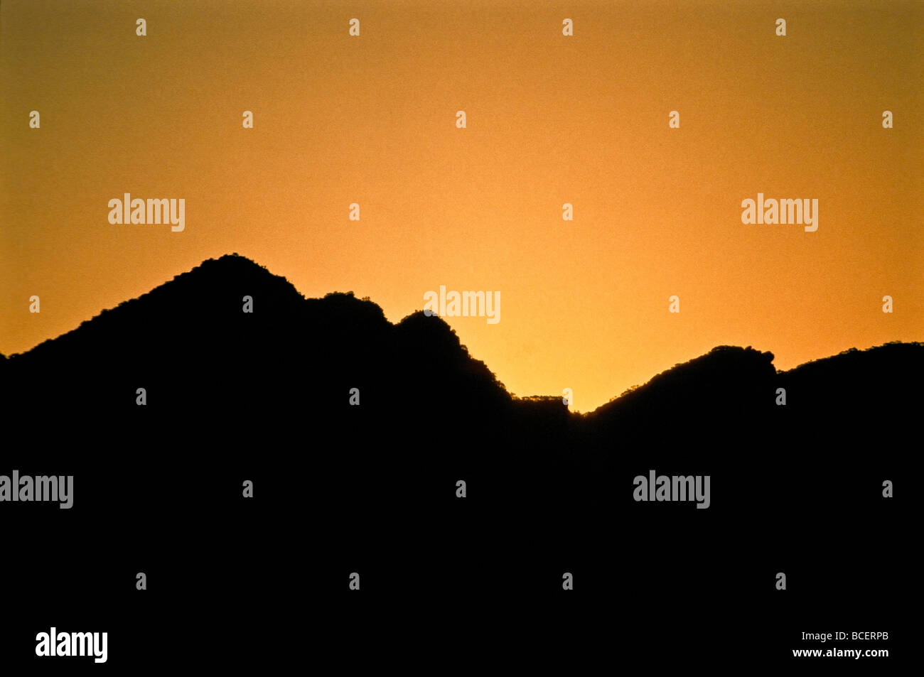 A rugged mountain ridge-line looks like teeth biting into the sunset. Stock Photo