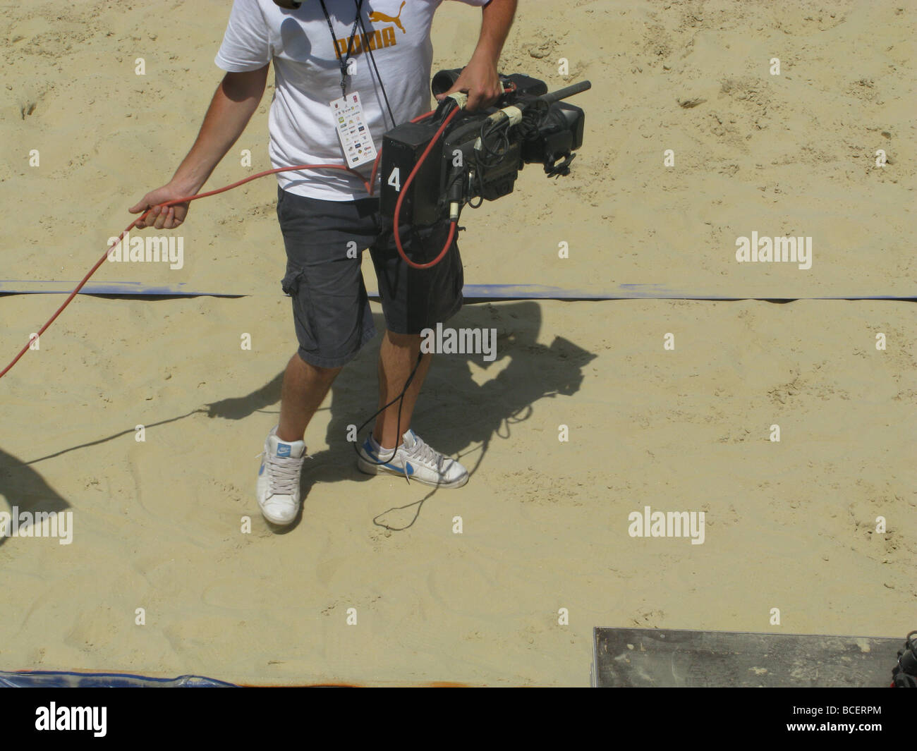 man with tv camera filming at beach event Stock Photo