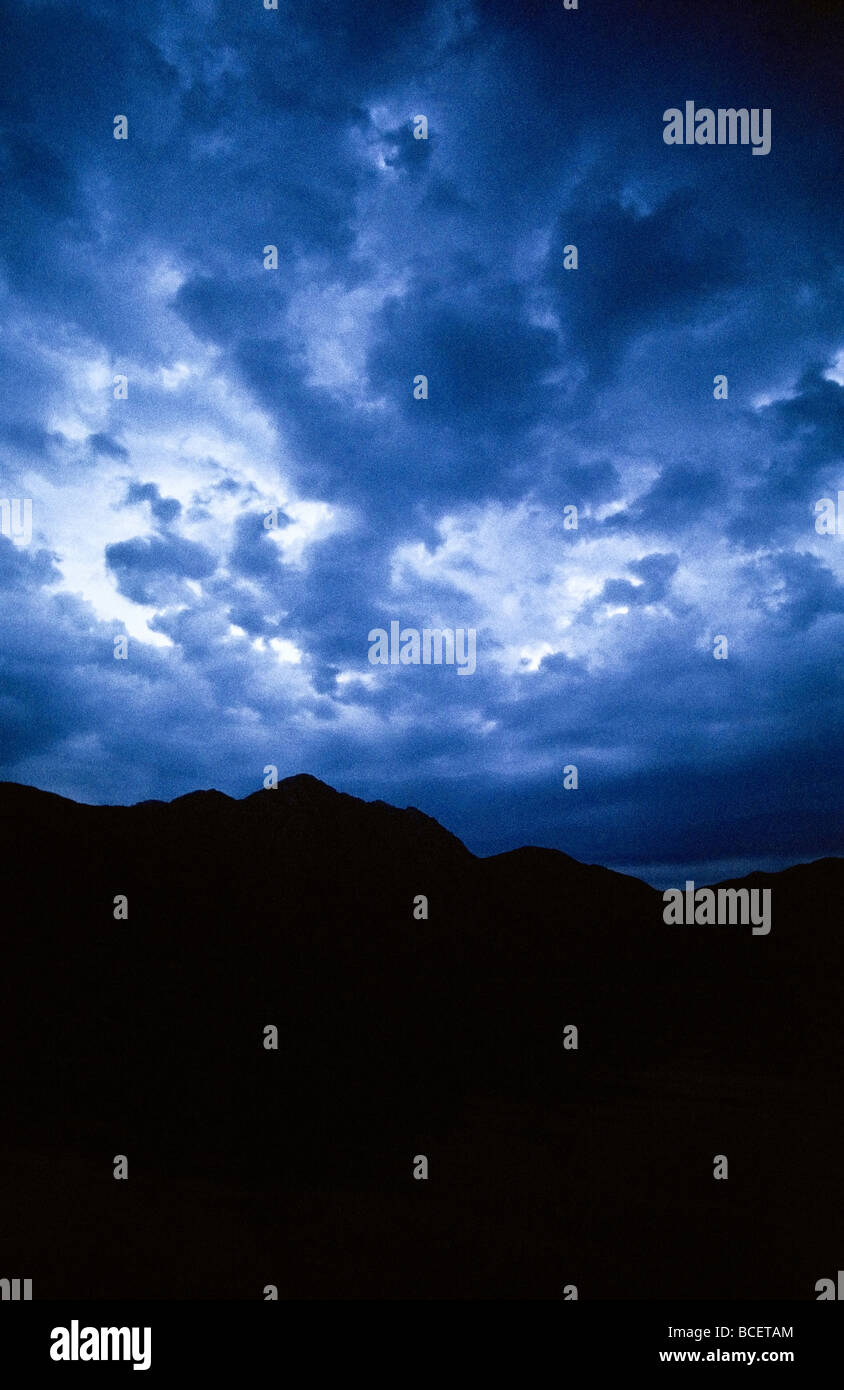 Dark, sinister storm clouds roil over a mountain range at night Stock ...