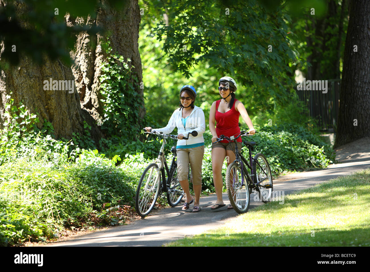 Mother and daughter walking bicycles at park Stock Photo