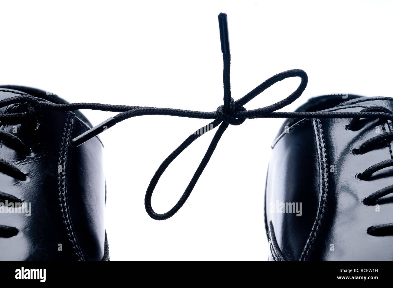 Horizontal close up of a pair of black leather business shoes with laces tied together Stock Photo