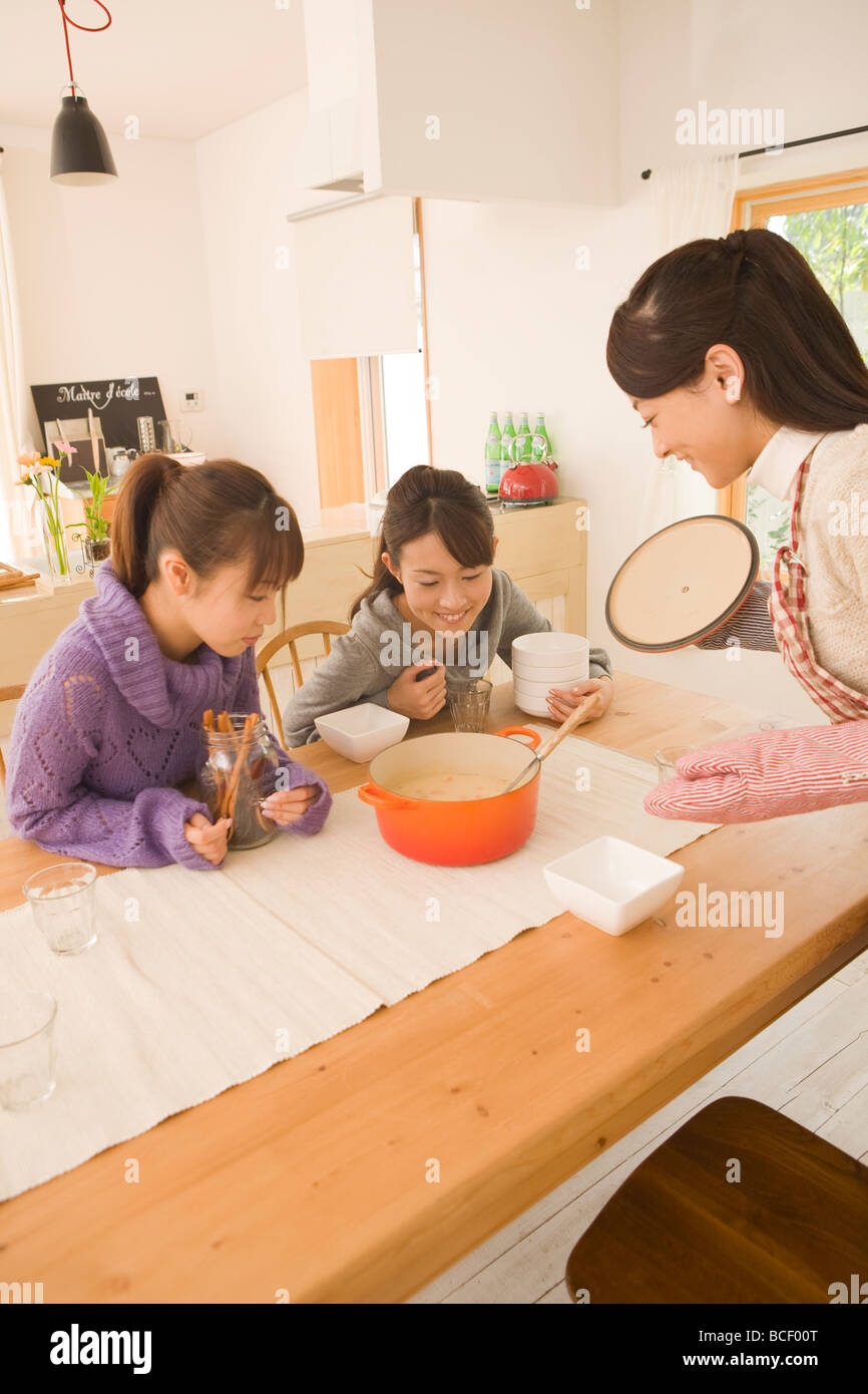 Three young women chatting at dinning table Stock Photo
