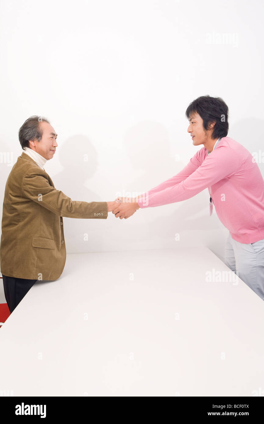 Mature man and young man shaking hands Stock Photo