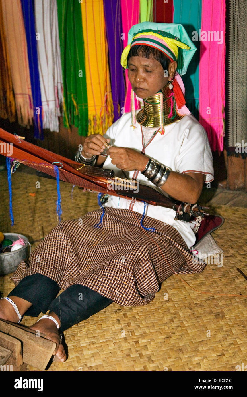 Myanmar, Burma, Lake Inle. A Padaung woman wearing a heavy brass necklace weaves cloth on a simple loom. Stock Photo
