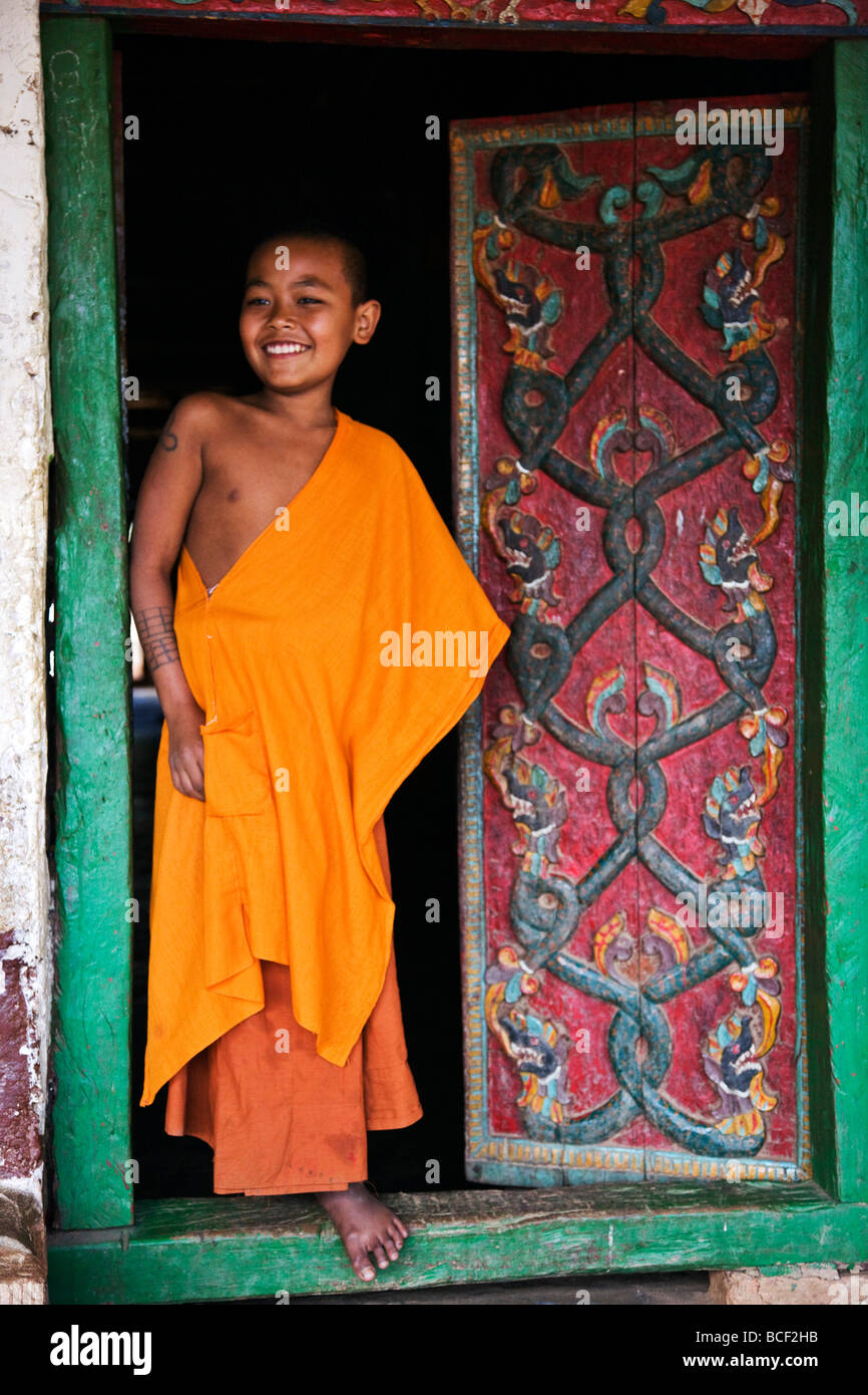 Myanmar, Burma, Ban-lo. A young novice monk at the carved doors of Ban-lo monastery outside Kengtung. Stock Photo