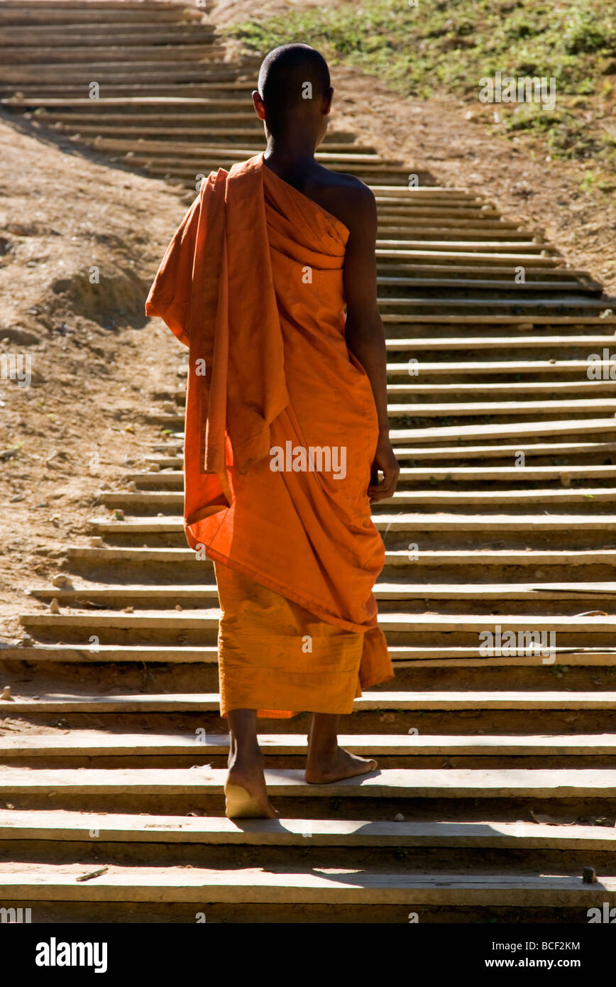 Myanmar, Burma, Loi pan. A monk in saffron robes walks up a long flight of wooden steps towards the Wan-seeing monastery. Stock Photo