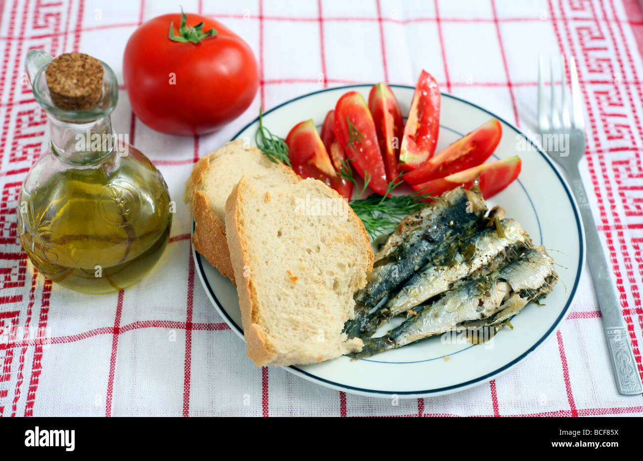 A healthy Mediterranean-style meal of baked sardines with bread, tomatoes and olive oil Stock Photo