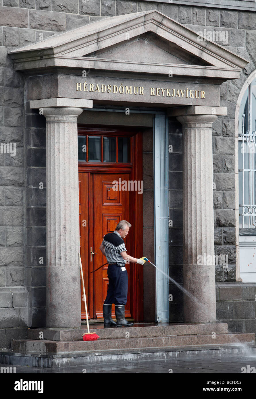 A man cleans the steps at Heradsdömur Reykjavikur, Reykjavík District Court, Reykjavík, Iceland Stock Photo