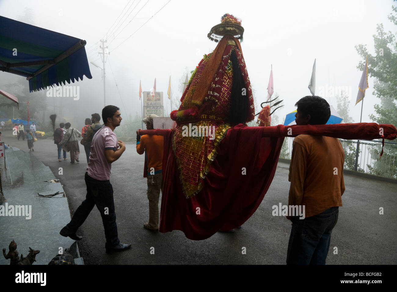 Hindu man pays his respects to a passing representation of a hindu god or deity / idol.  McCleod Ganj. Himachal Pradesh. India. Stock Photo