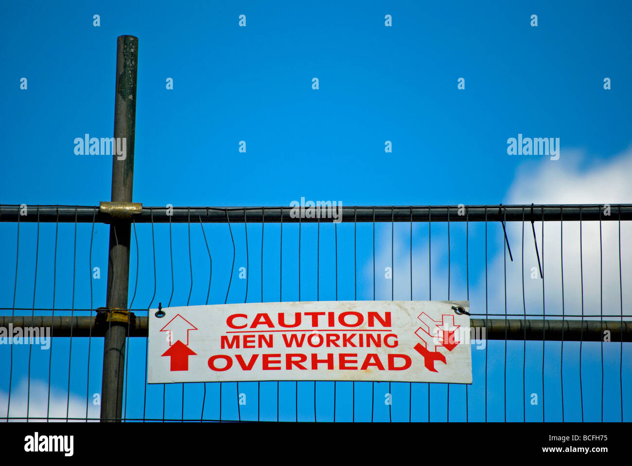 caution men working overhead sign on scaffolding at a building site in ...