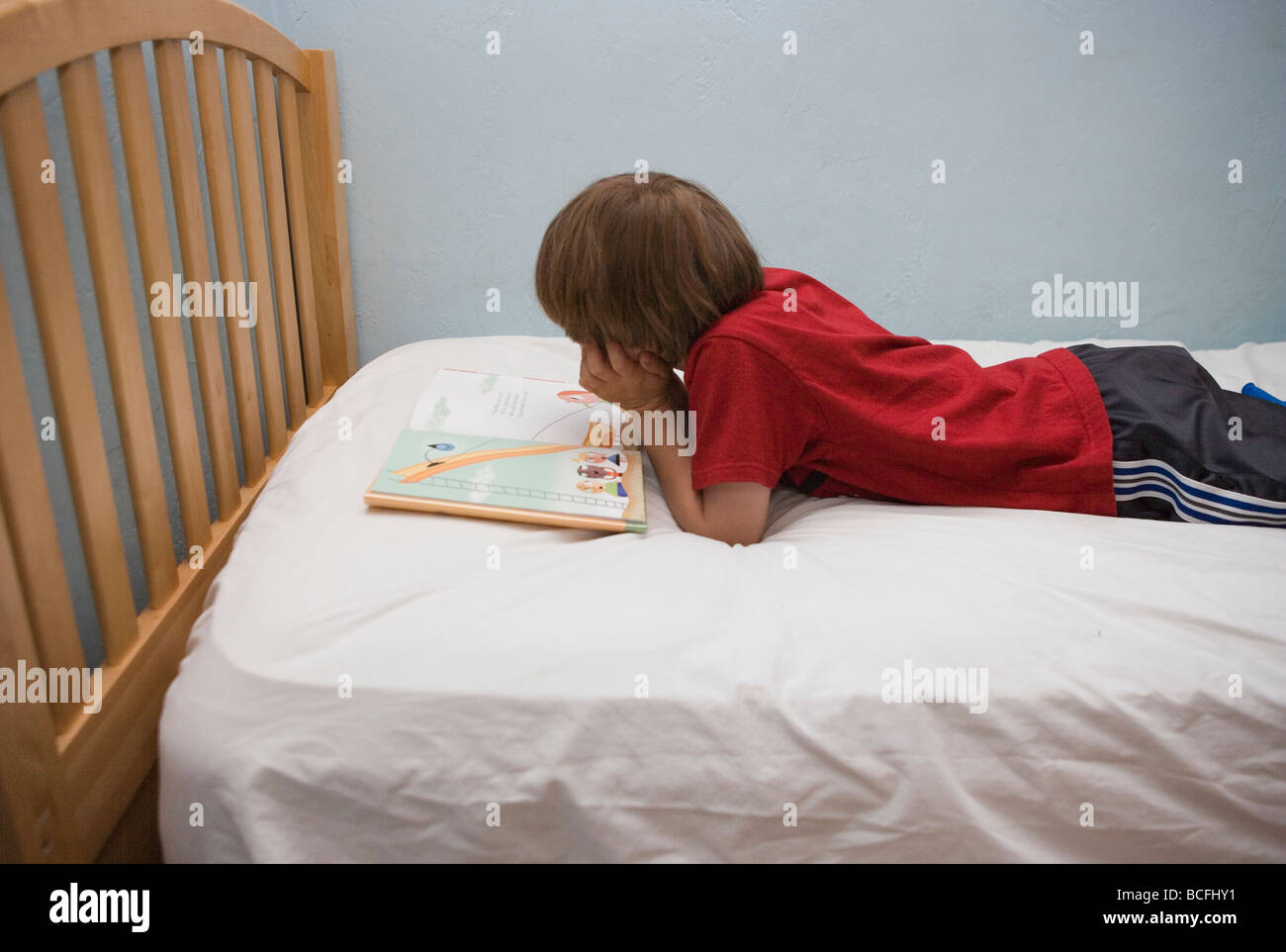 seven year old boy reading a book in bed Stock Photo Alamy