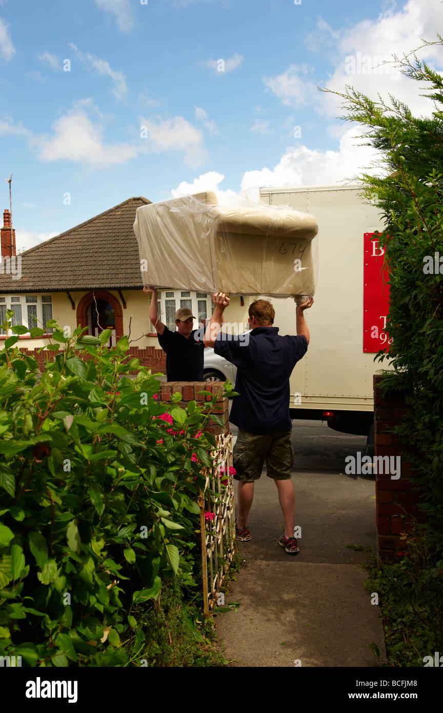 House and Furniture removals with removal men carrying loads sofa settee Stock Photo