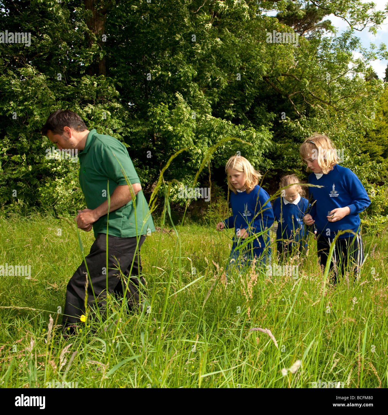 education officer with the Forestry Commission in wales leading a group of primary school children on a bug hunting nature trail Stock Photo